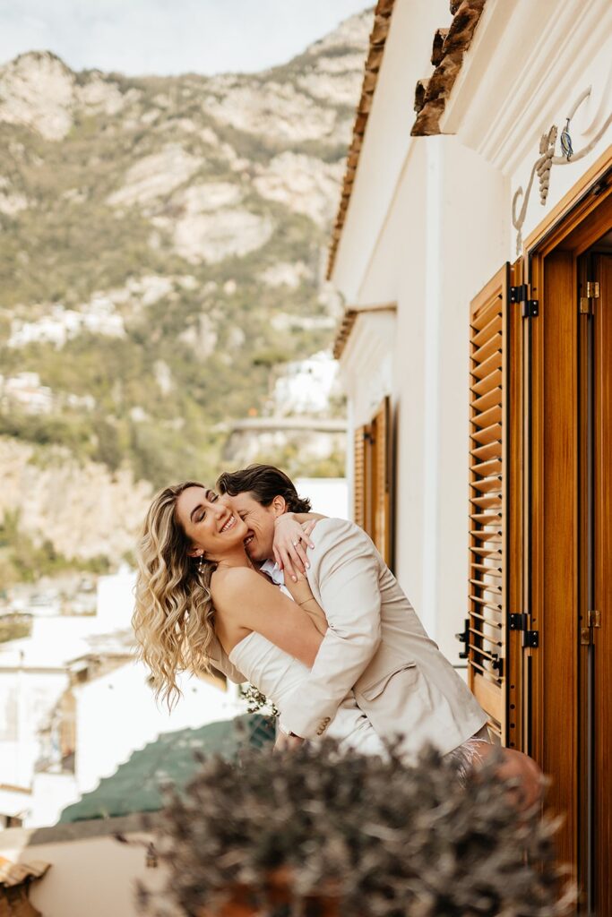 Bride and groom hug on a Tuscan-inspired East Coast wedding venue balcony.