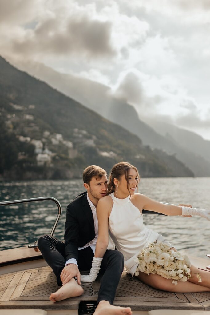 Bride and groom sit on the deck of a boat while riding to their private island wedding resort