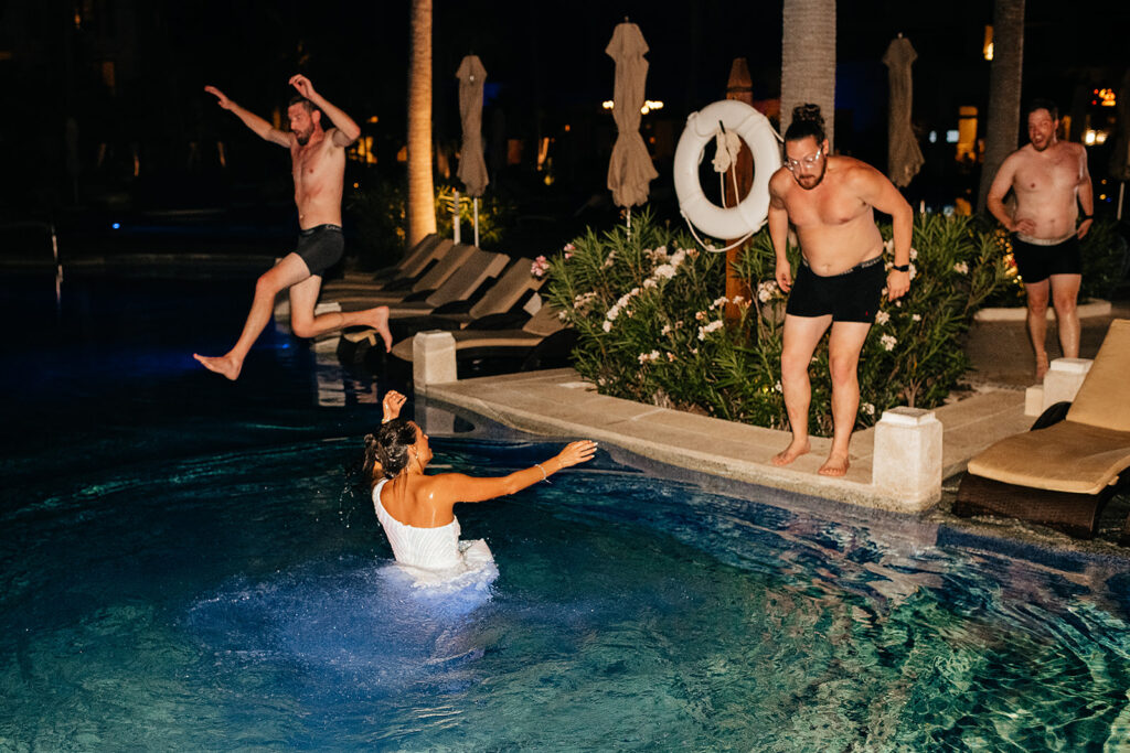 Wedding guests jumping into pool