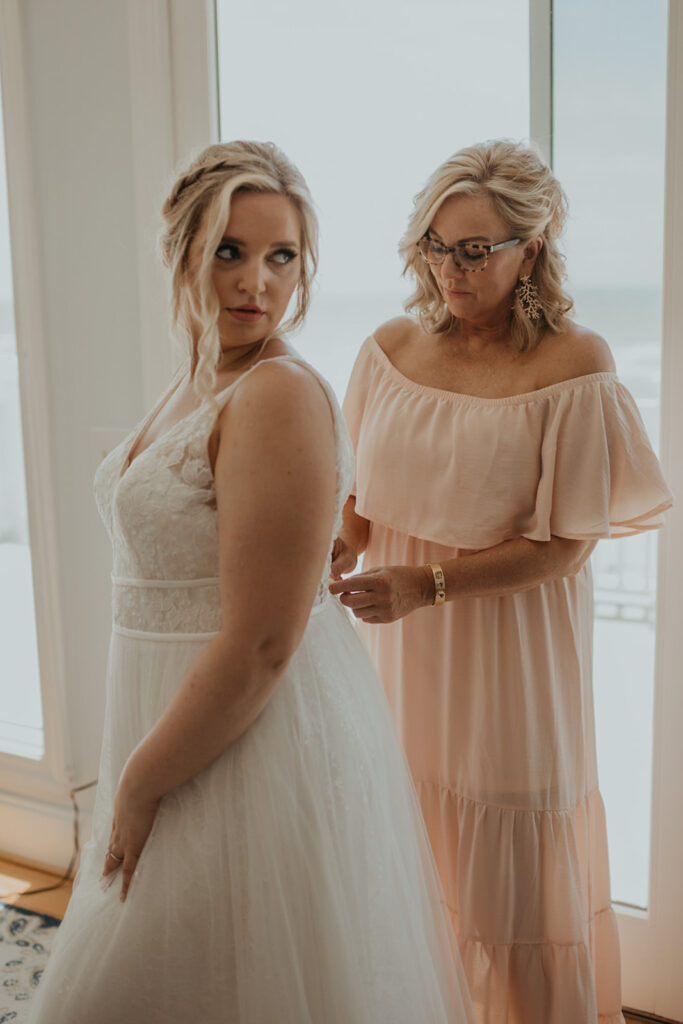 Bride getting dressed with mother before wedding 