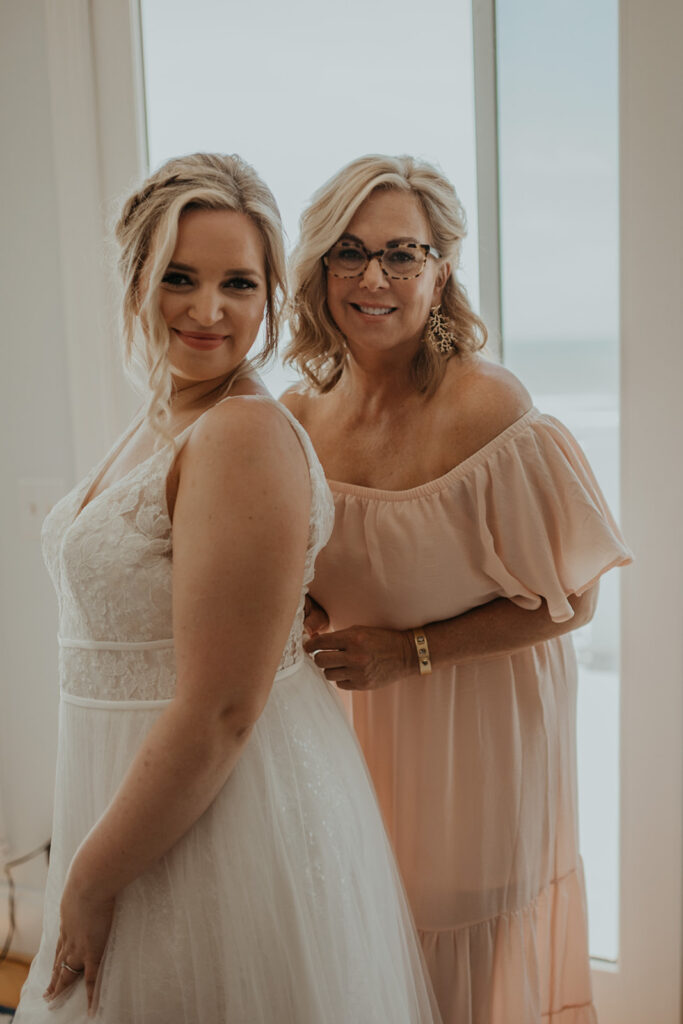Bride getting dressed with mother before wedding 
