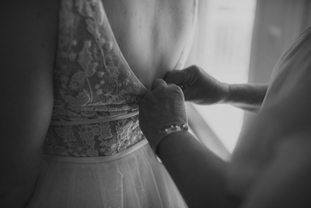 Bride getting wedding dress zipped
