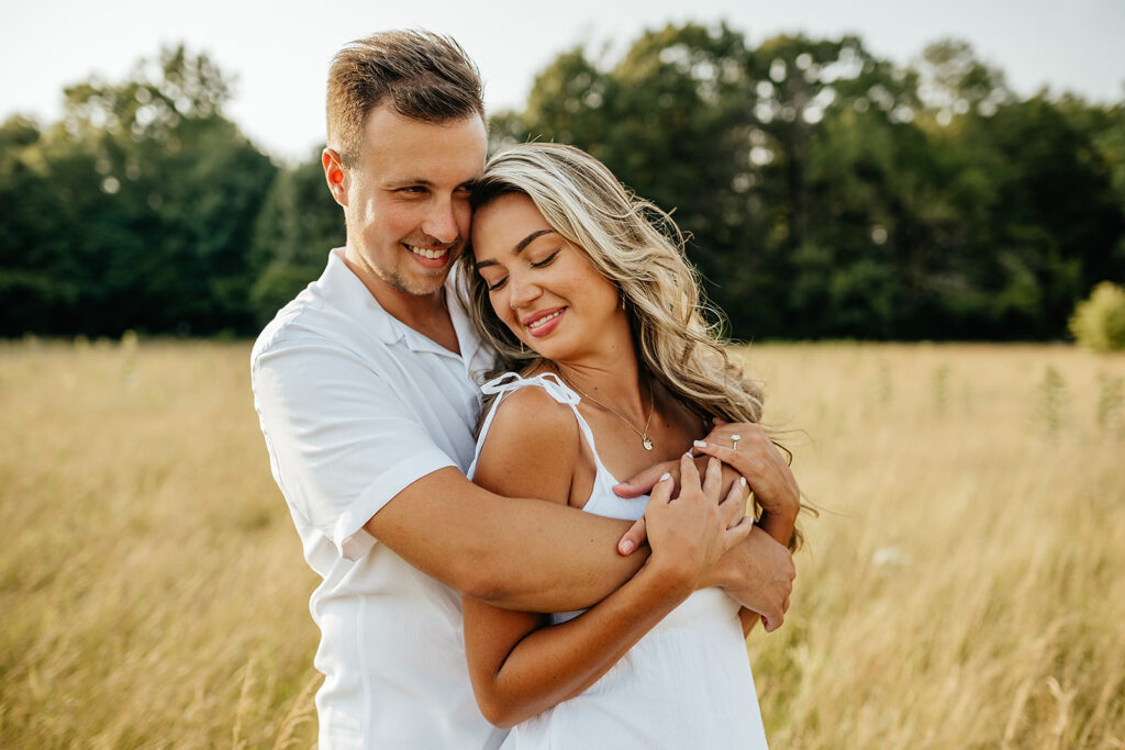 cute couple hugging in field for engagement photos