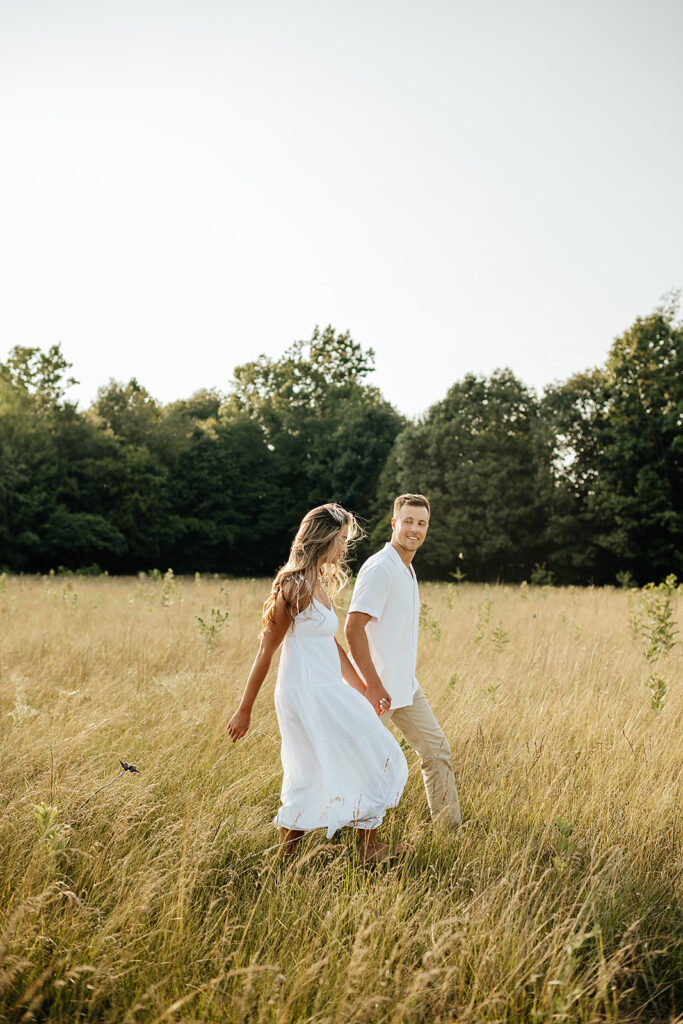 couple running in field for engagement photos