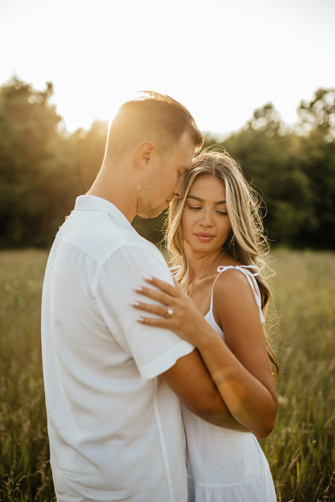 couple hugging in field for engagement photoshoot in Mete Park