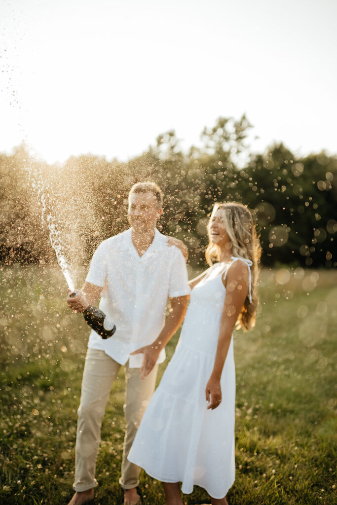 couple popping champagne for engagement session photos
