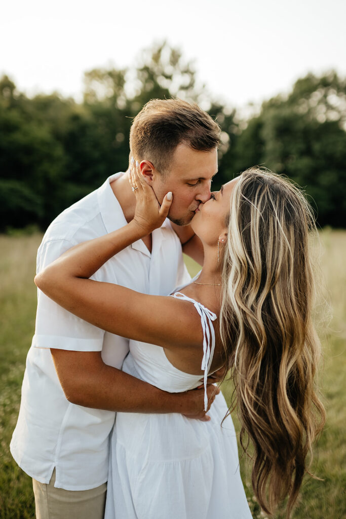 couple kissing in field for engagement photoshoot