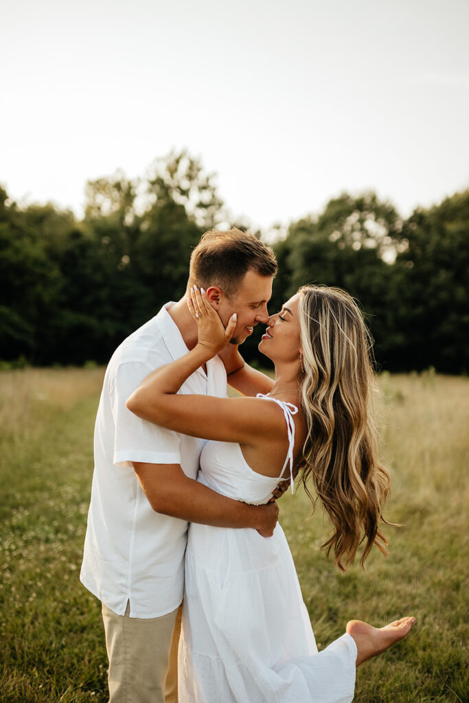 couple kissing in field for engagement photoshoot