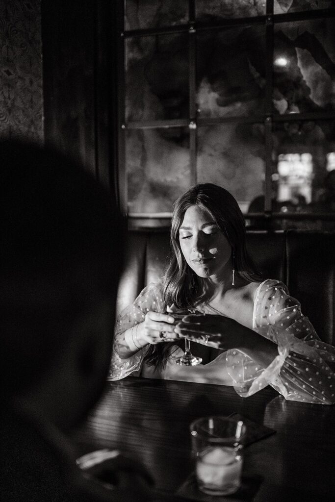Couple sits at a dimly lit booth in a bar during their hotel engagement photos