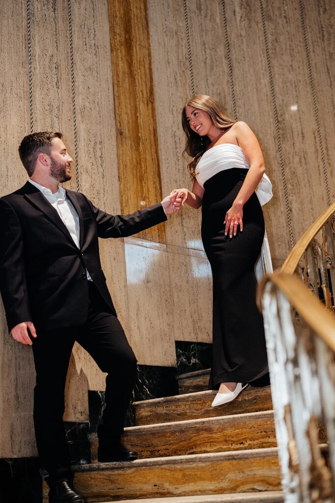 Man holds woman's hand while walking down the stairs at Bottleworks Hotel