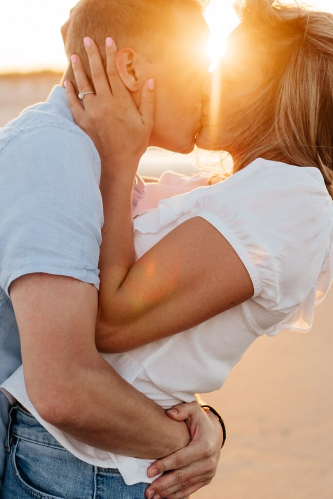 Couple kisses during their beach engagement session in Folly Beach, South Carolina
