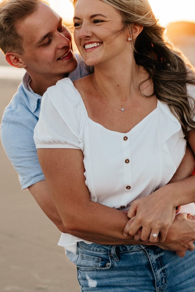 Couple hugs during their beach engagement photos in Folly Beach, South Carolina