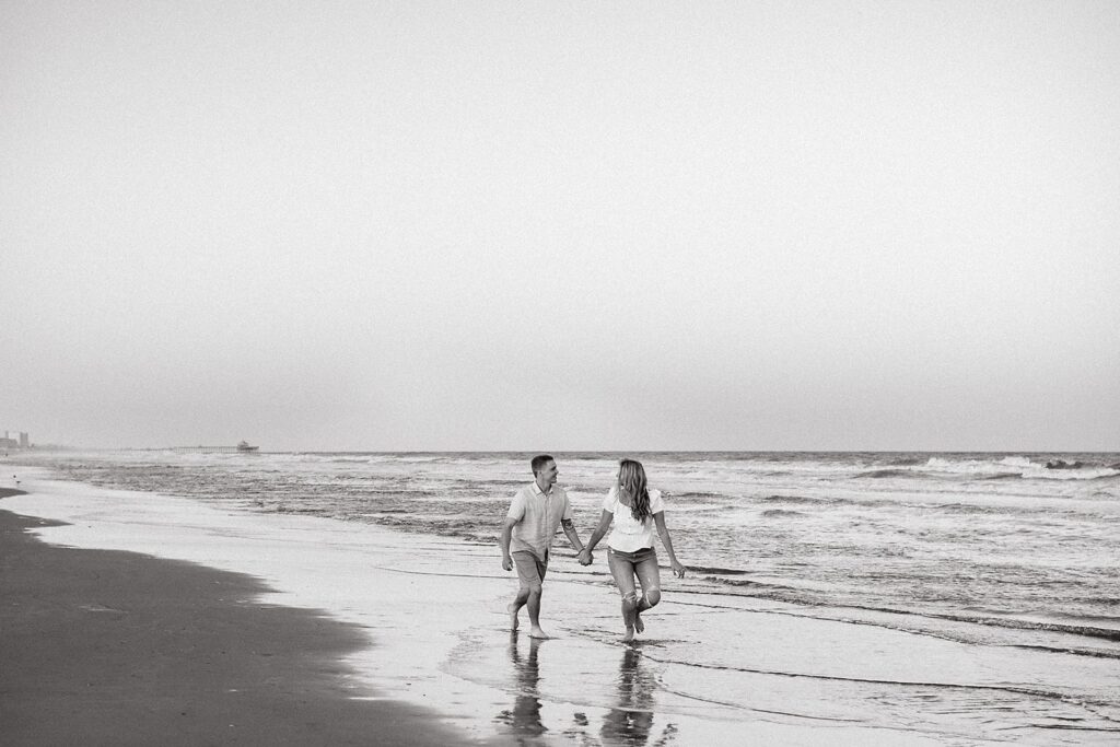 Couple holding hands while running across the beach during their Charleston engagement
