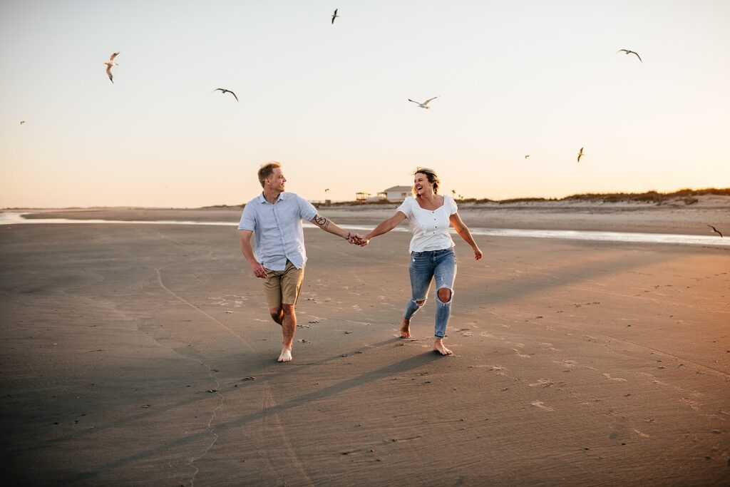 Couple holds hands and runs across the beach during their Charleston engagement photos