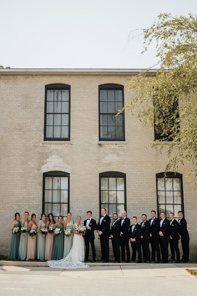 Bride and groom stand with their wedding party outside an East Coast wedding venue