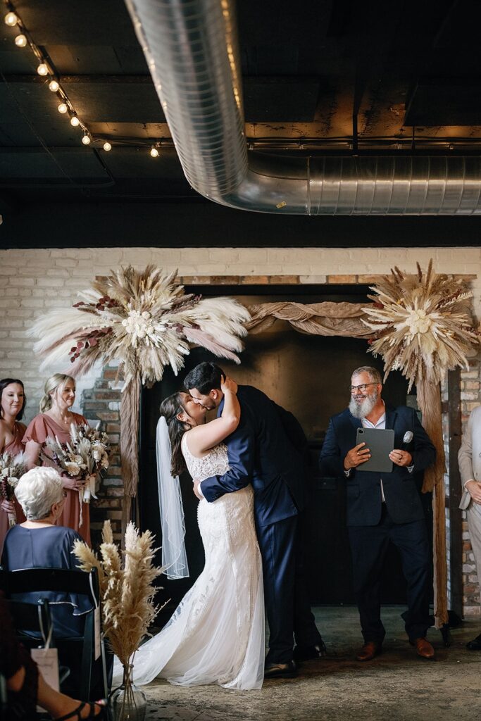 Bride and groom kiss at the altar during their indoor wedding ceremony in Indiana