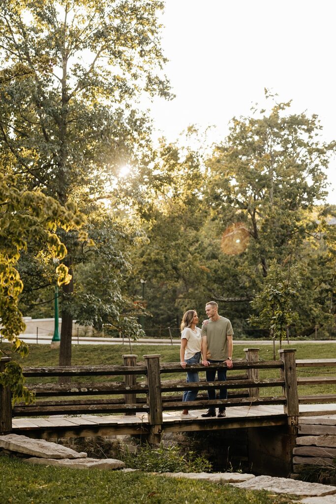 Man and woman stand on a wood bridge during their Indiana University engagement photos
