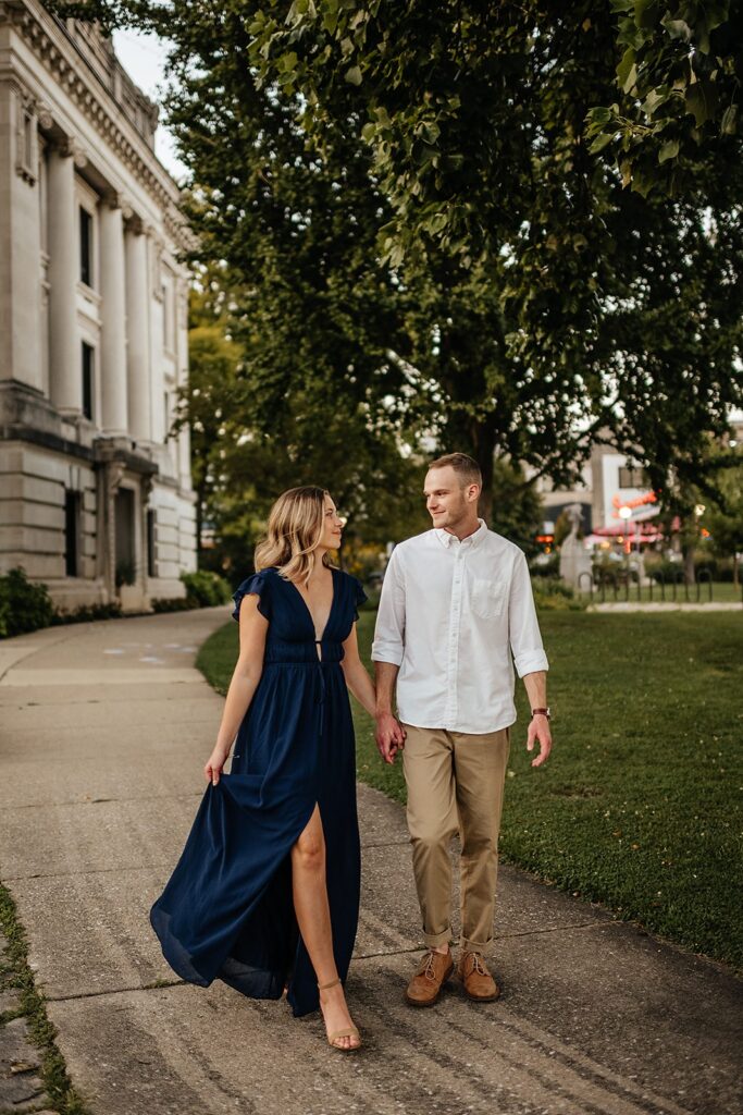 Man and woman hold hands while walking across campus during their Indiana University engagement session