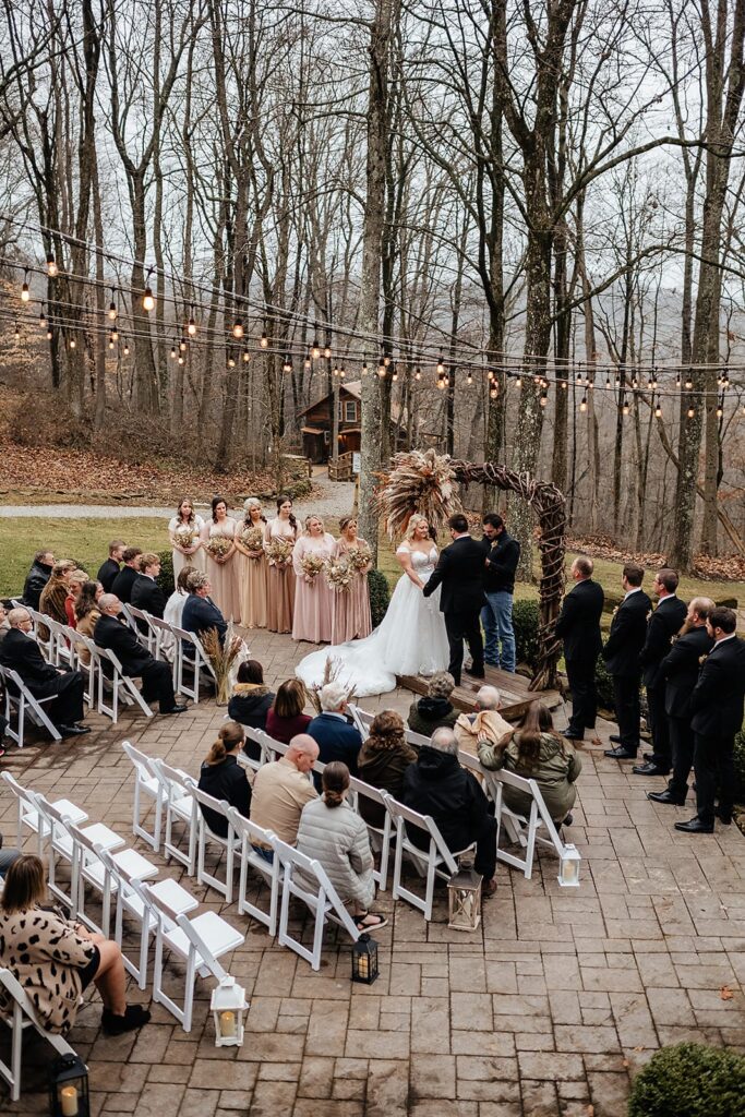 Bride and groom hold hands during their micro wedding ceremony with guests