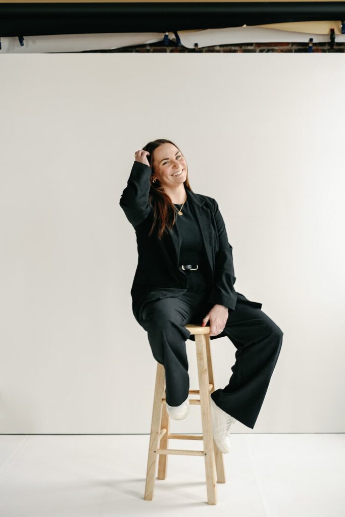 Wedding content creator sitting on a wood stool in a studio for her branding photos