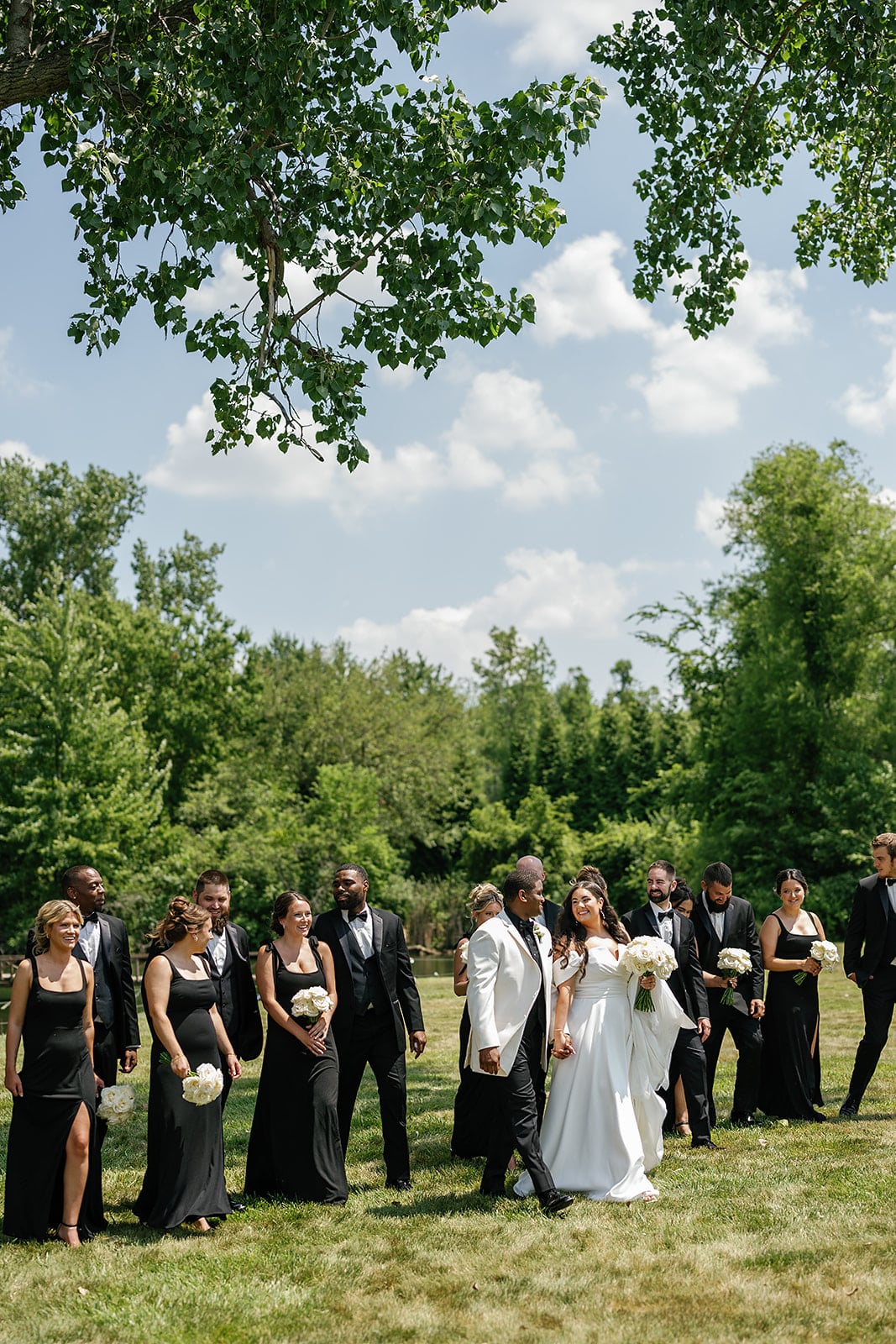 Bride and groom walk across the lawn during their midwest wedding portraits with their wedding party 