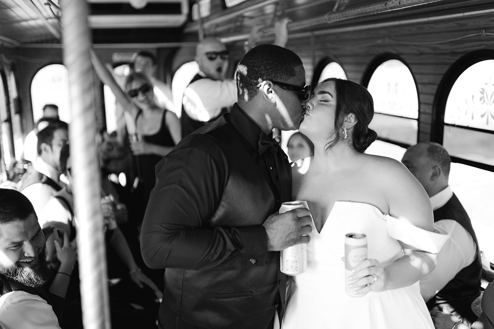 Bride and groom kiss on a trolley during cocktail hour with their wedding party 