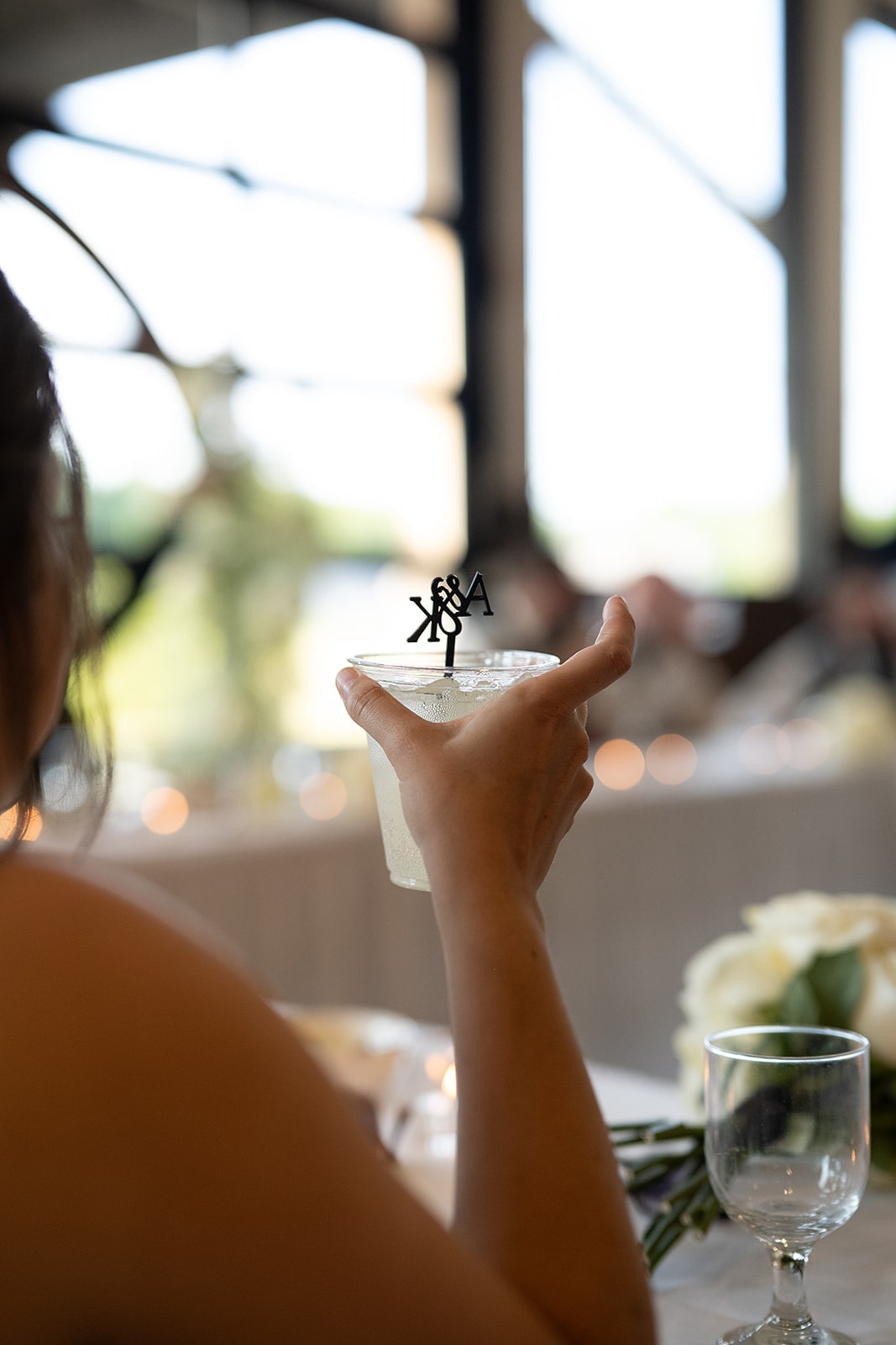 Bride holds a cocktail with a custom stir stick 