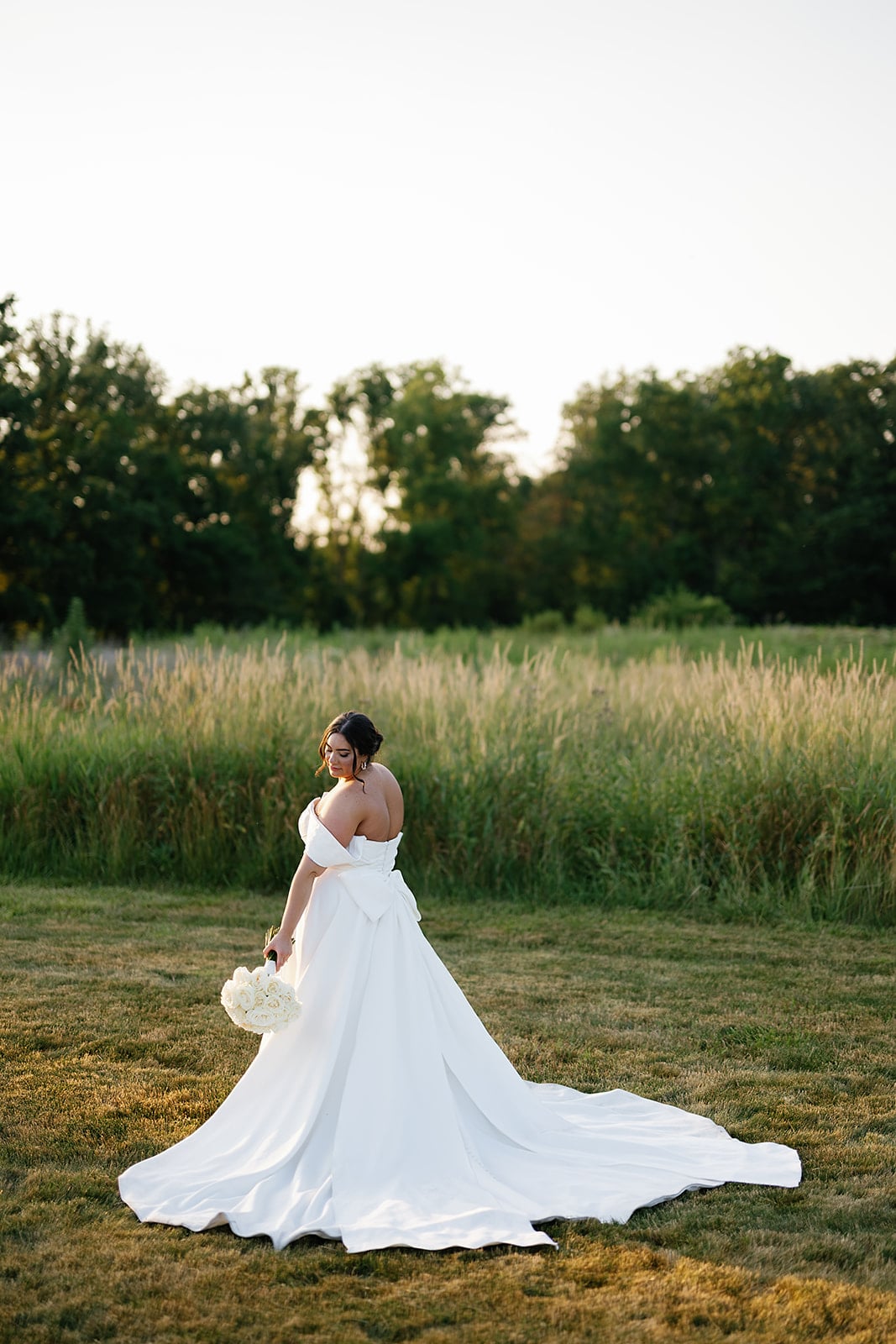 Bride stands in a field during sunset for her bridal portraits 