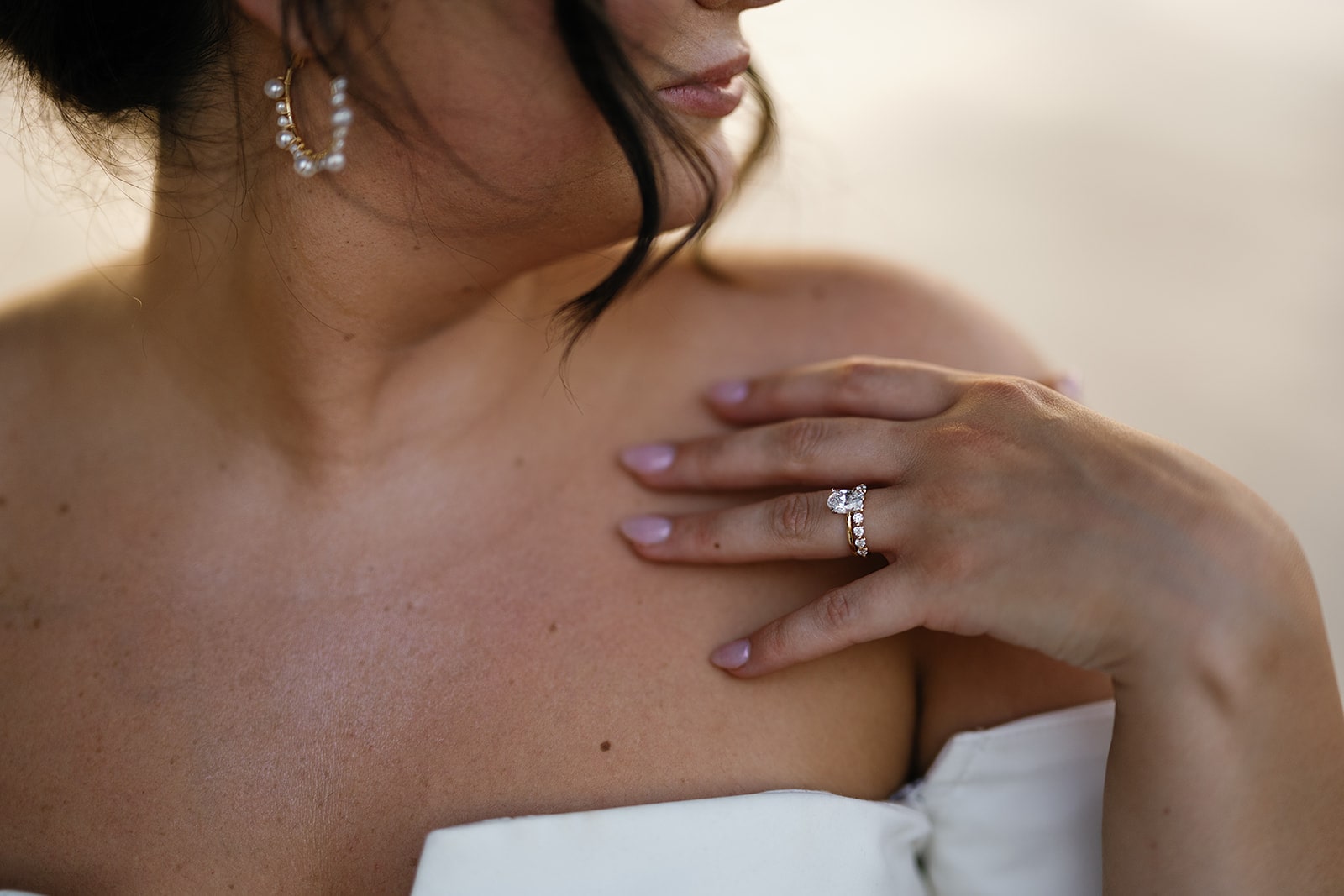 Bride wearing white chiffon wedding dress and white diamond rings with pearl and gold earrings