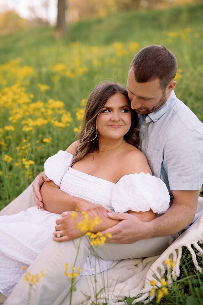 Couple sits in a wildflower field during their Newfields engagement session in Indianapolis