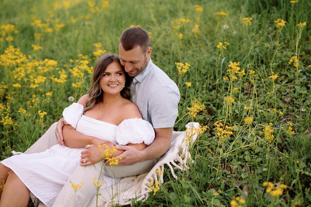 Couple sits in a wildflower field during their Newfields engagement session in Indianapolis