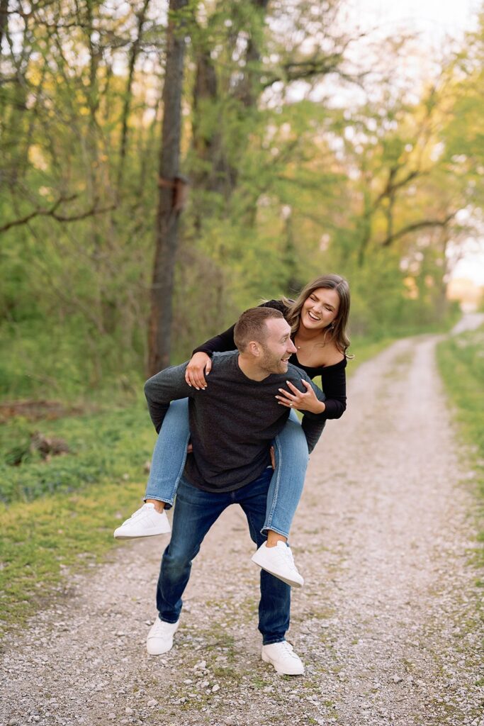 Man carries woman on his back during their Newfields engagement photo session