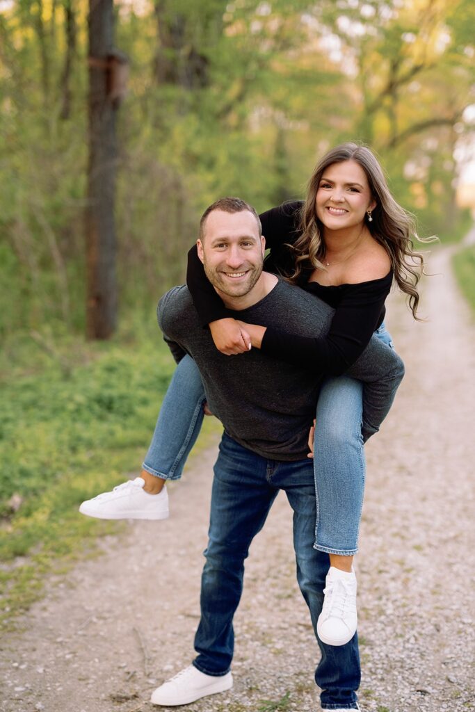 Man carries woman on his back during their Newfields engagement photo session