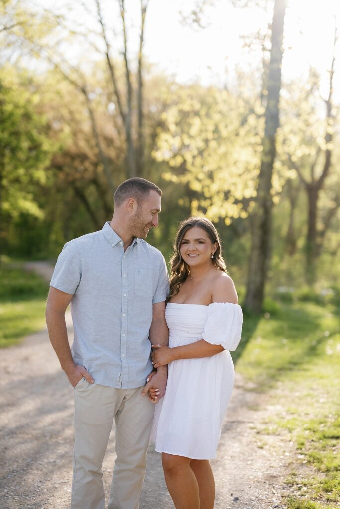 Man and woman hold hands on a trail during their engagement session at Newfields