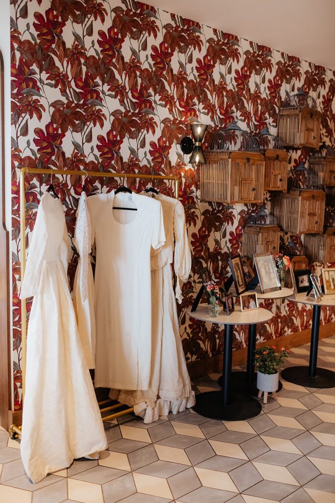 Vintage wedding dresses hanging from a gold rack with vintage wedding photos displayed nearby