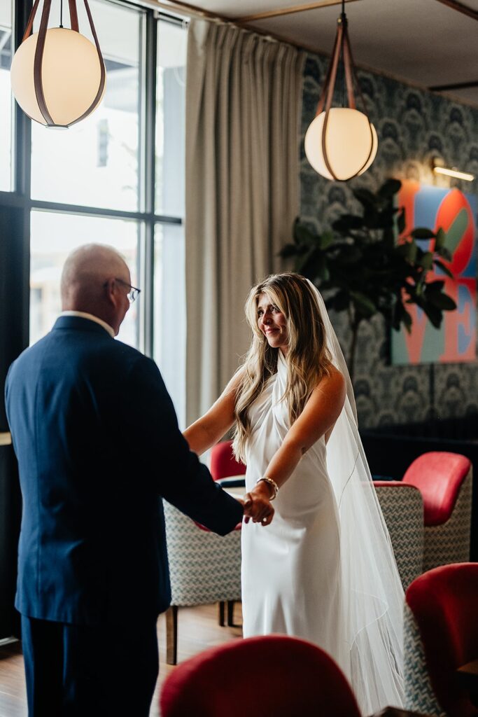 Bride and father hold hands after their wedding first look 