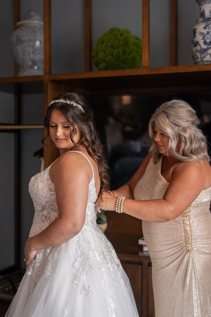 Brides mother helping to zip up her wedding dress