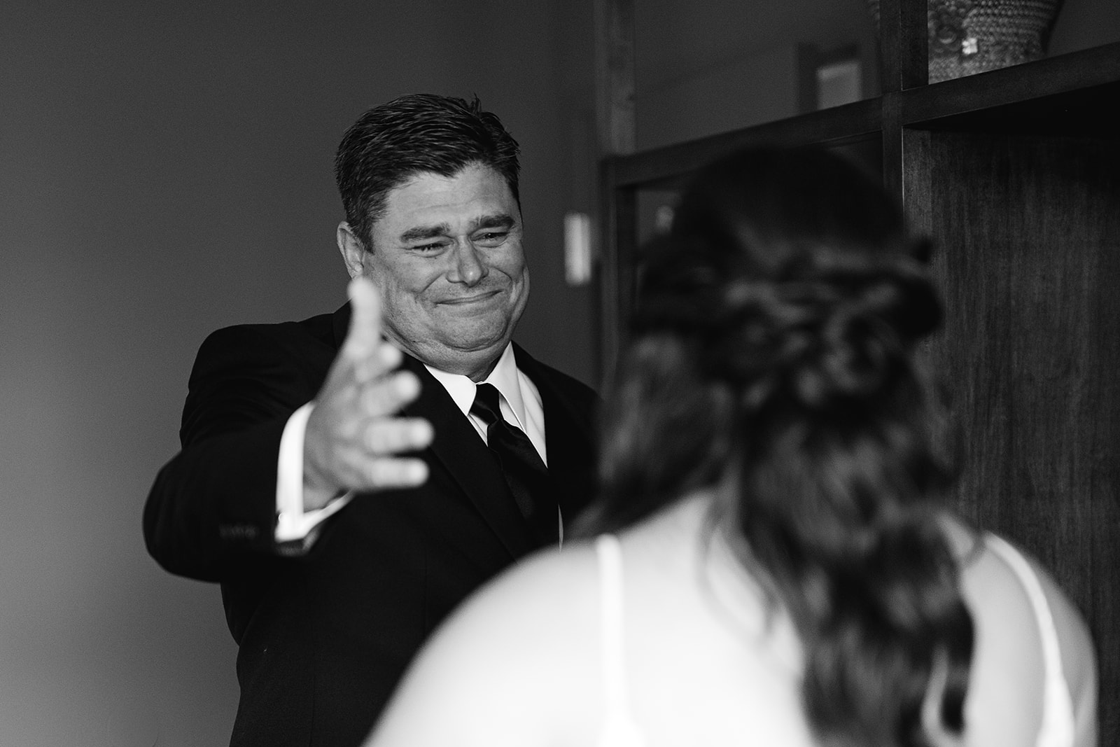 Black and white image of a bride sharing an emotional first look with her father