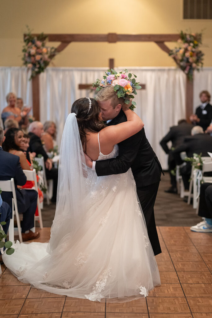 Bride and groom end of aisle dip kiss