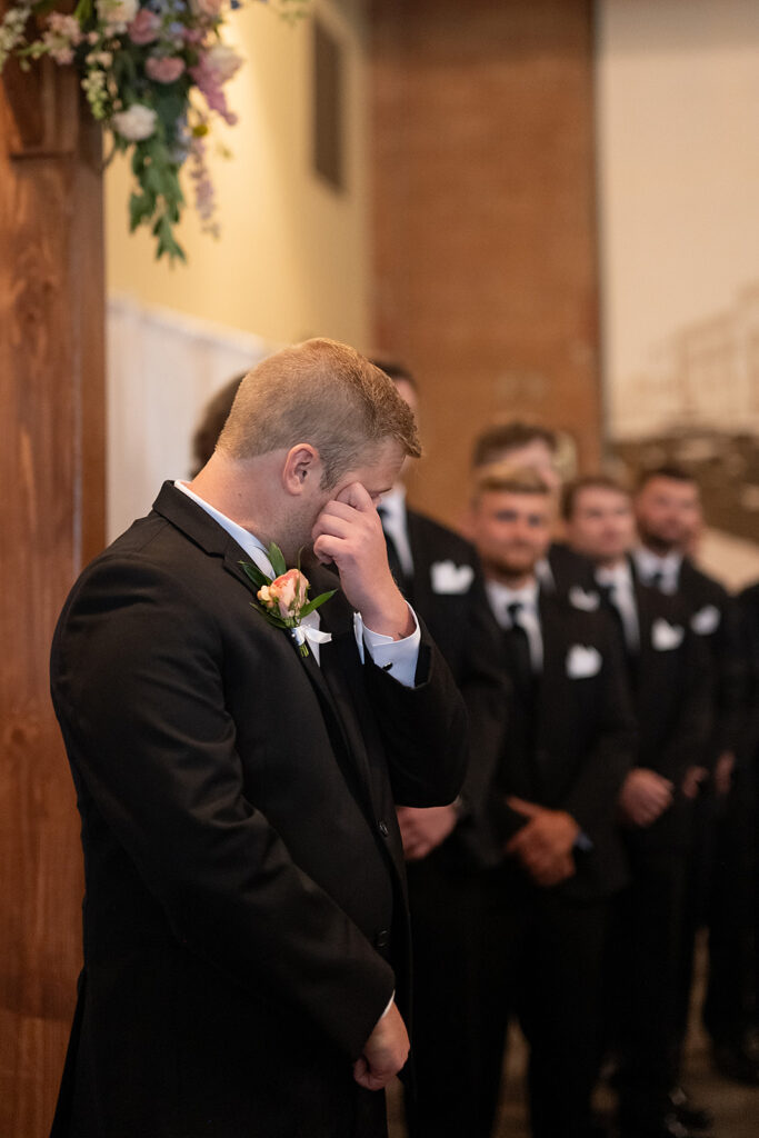 Groom getting emotional as he sees his bride walking down the aisle towards him