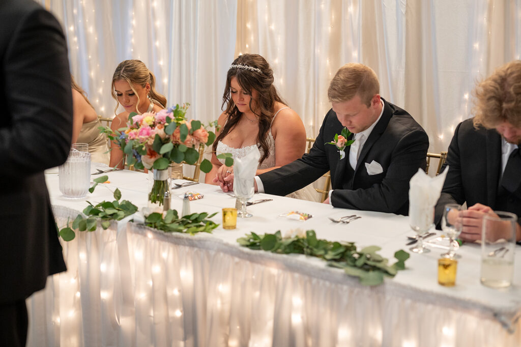 Bride, groom and their guests praying during the reception