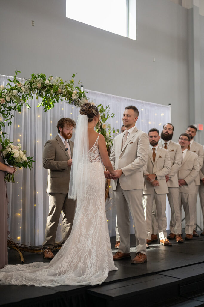 Bride and groom holding hands during their wedding ceremony.