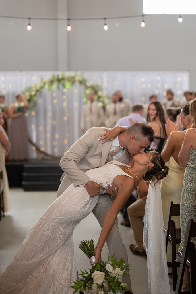 Bride and grooms end of aisle dip kiss during their Kruse Plaza wedding ceremony