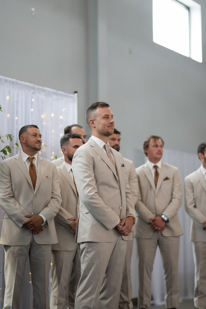 Groom smiling as he sees his bride walking down the aisle towards him