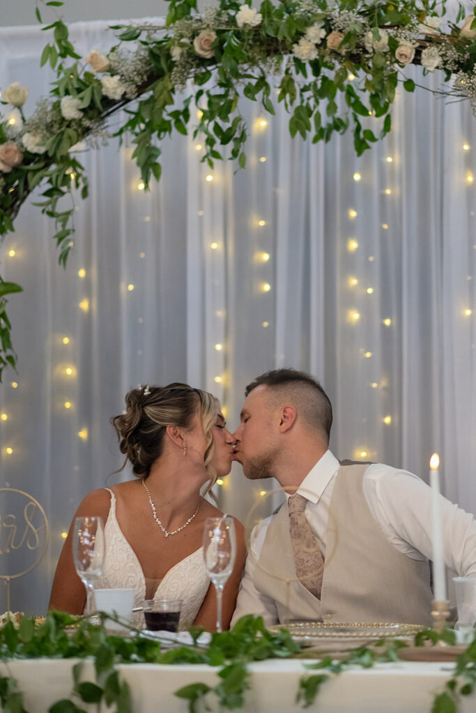 Bride and groom kissing at their table