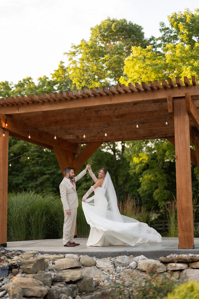 Bride and groom dancing under a wooden pergola at Stone Creek Lodge wedding venue