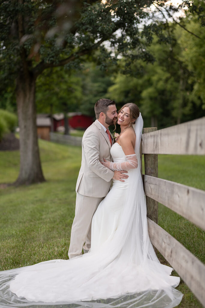 Bride and groom posing against a wooden fence at Stone Creek Lodge