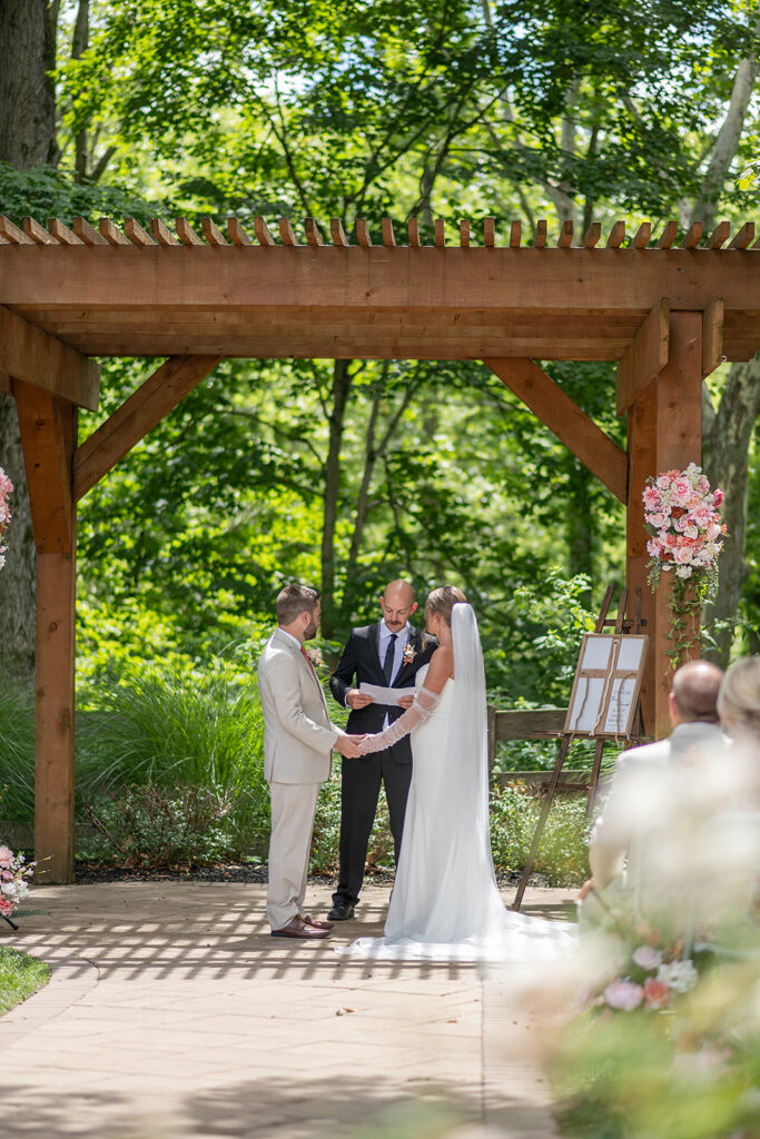 Bride and groom holding hands during their outdoor Stone Creek Lodge wedding ceremony