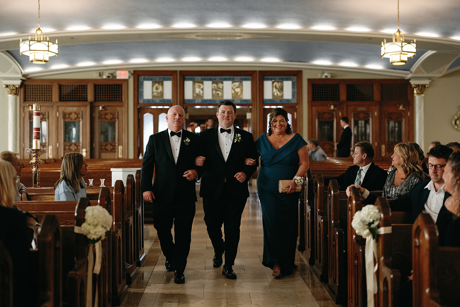 Groom walking down the aisle with his parents