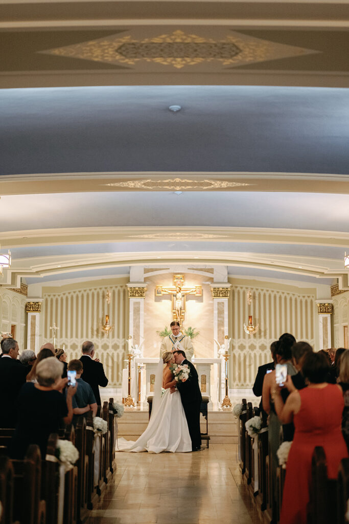 Bride and groom kissing during their Catholic wedding ceremony